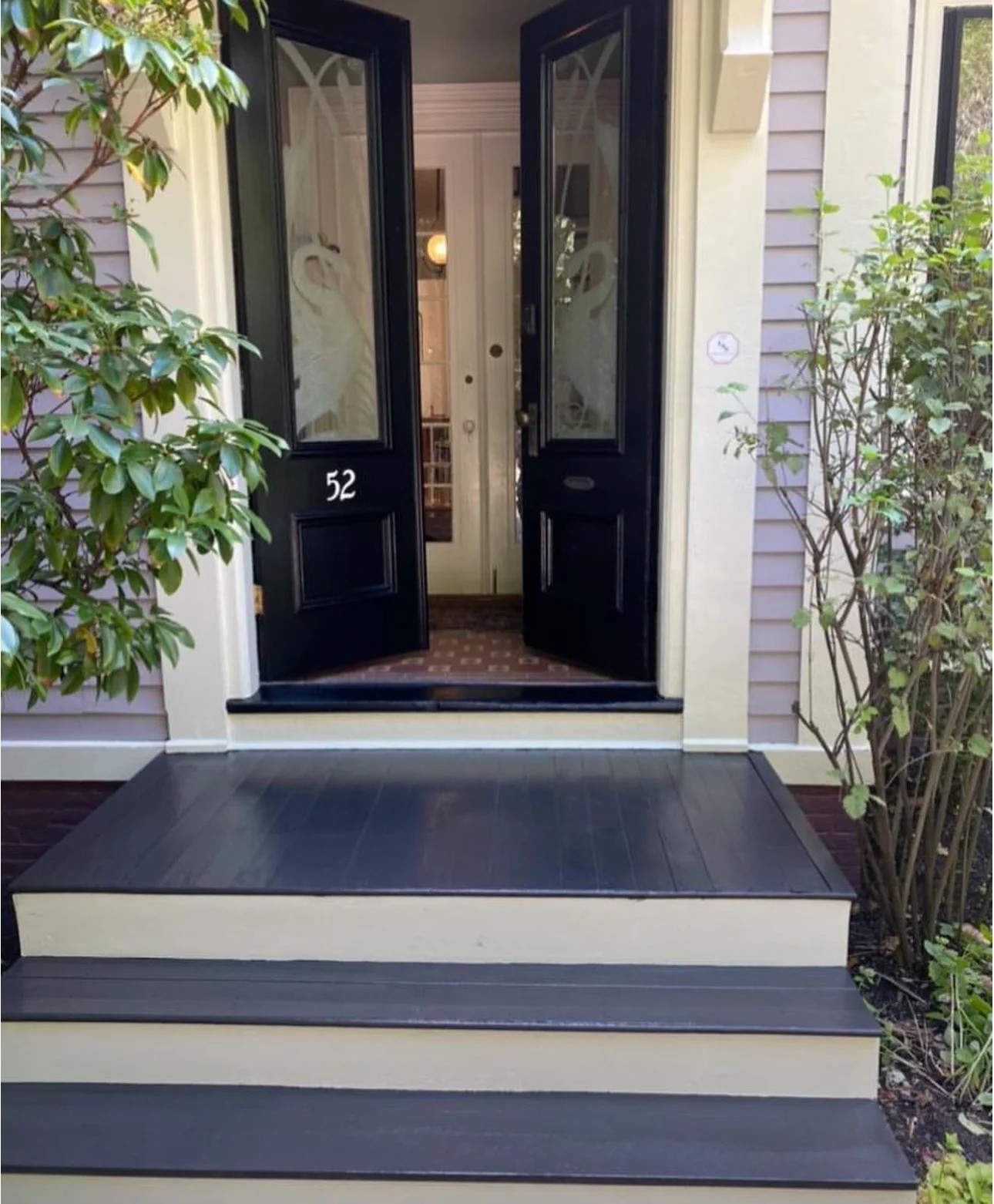Freshly painted black front doors, porch and steps